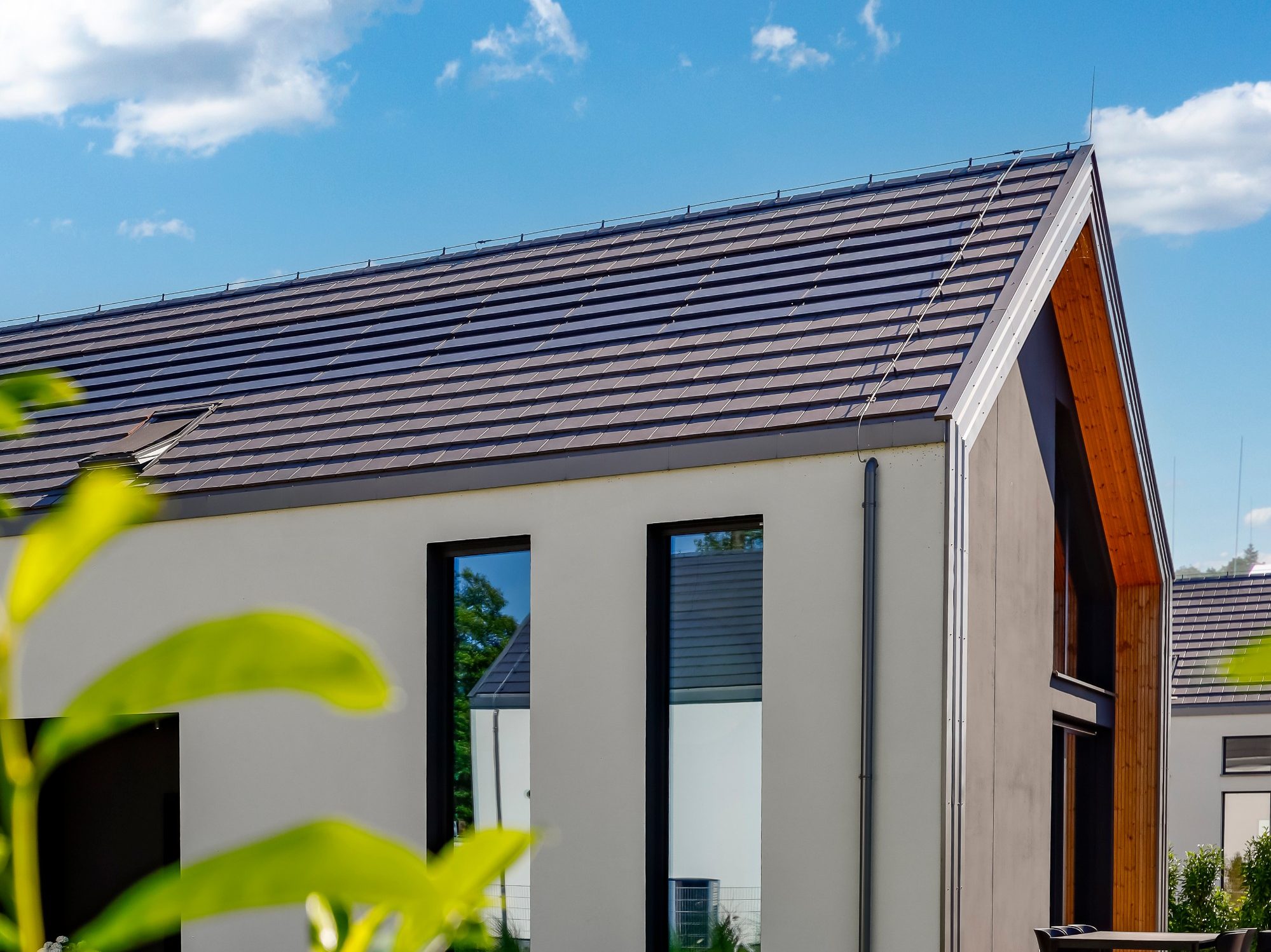 Dom z panelami fotowoltaiczynymi Wevolt X-Tile w kolorze czarnym i płaską dachówką ceramiczną Orea 9 w kolorze szarej angoby